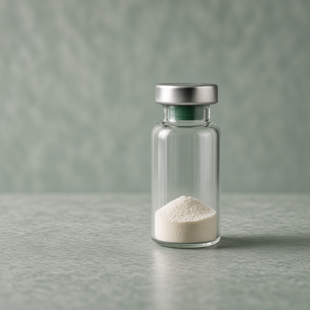 Clear glass research vial with a green neck band and a low mound of powder, on sage stone.